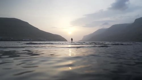 Man Standing At Sunrise In Shallow Lake