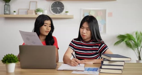 Portrait of Two Asian schoolgirl studying online making notes in copybook