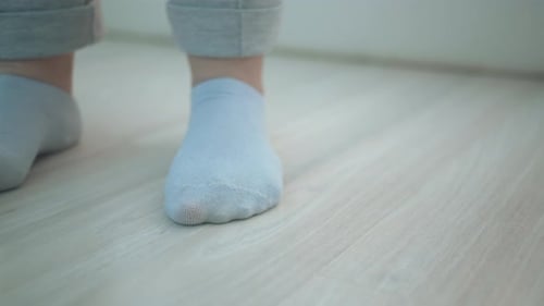 Feet in Socks Standing on Wood Floor Indoors