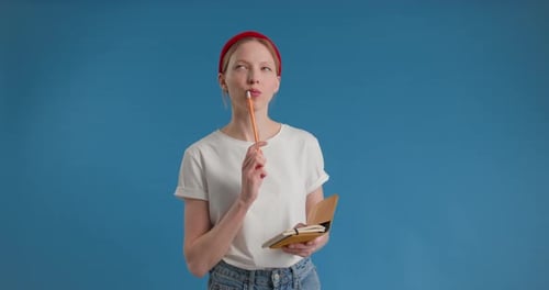 Woman Writing in a Notebook on Blue Background