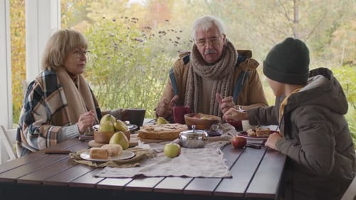 Family Sharing Meal at Outdoor Table in Autumn
