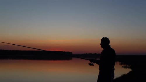 Ein Mann beim Angeln wirft die Angelrute Sunset Silhouette