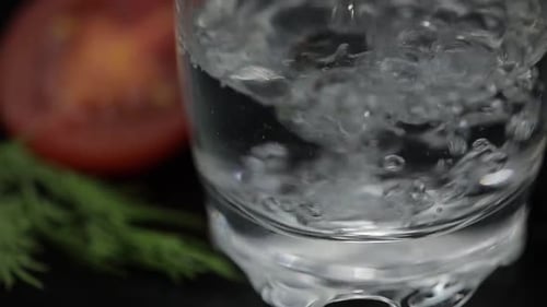 Pour Alcohol Drink Vodka From a Bottle in Shot Glass. Surface with Snacks