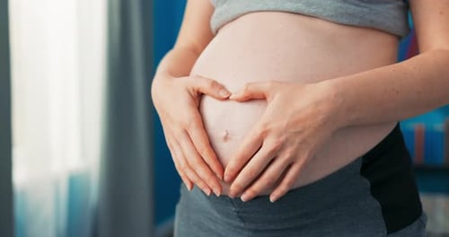 Gros plan de l'abdomen d'une femme dans une grossesse avancée le dernier trimestre debout par la fenêtre