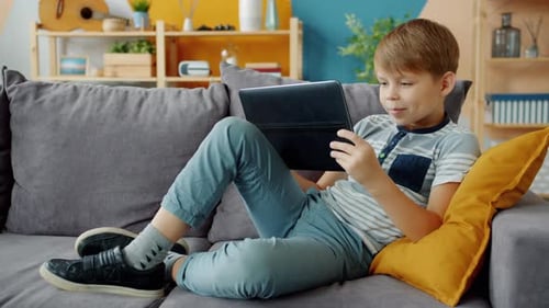 Boy Relaxing on Couch Using Tablet at Home