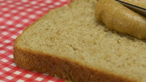 Spreading Peanut Butter on Bread Slice with Knife