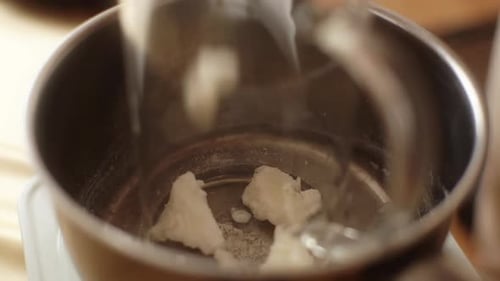 Closeup of Unrecognizable Female Artisan Adding Dry Ingredient in Glass Jar Into Pot of Boiling