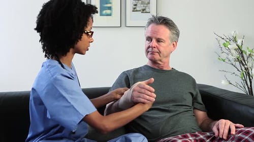 Nurse Bandaging Patient's Hand During Home Visit