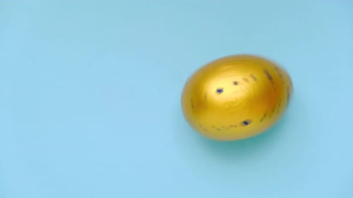 Golden Easter Egg Turning on Blue Background