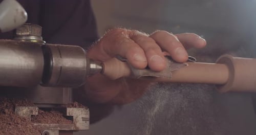 Woodworker Smooths Wood with Sandpaper on Lathe