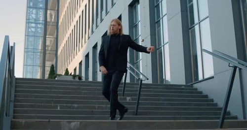 Fröhlicher Geschäftsmann in stilvollem Anzug tanzt und lächelt, während er Erfolg feiert, gutaussehender Mann