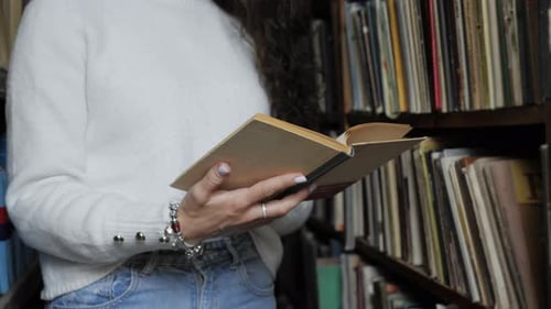 Junge Studentin liest ein Buch in der alten Bibliothek in Nahaufnahme