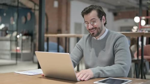 Young Man Talking on Video Call on Laptop in Office
