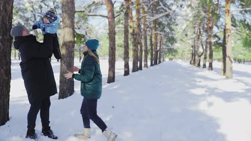 Young Mother and Father Plays with Their Little Son in Winter Park