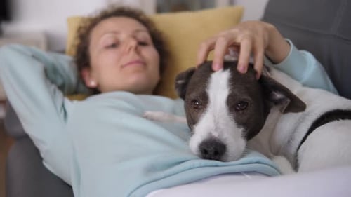 Woman Relaxing with Pet Dog on Sofa Indoors