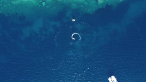 aerial view of a fast speedboats driving around in the circle and making beautiful shapes