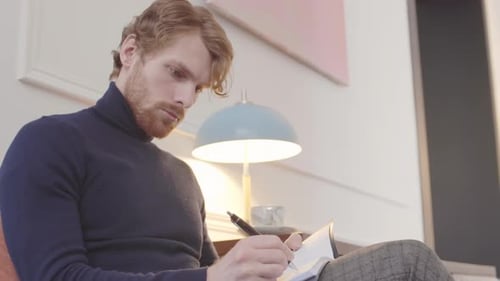 Young Man Writing in Journal Indoors