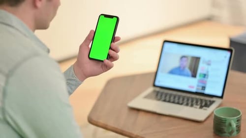 Young Adult Using Phone With Green Screen at Home