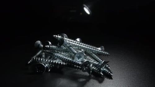 Pile of Silver Screws on Dark Background