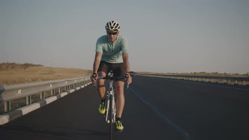 A Male Cyclist Rides Along the Highway on a Bike Lets Go of the Steering Wheel and Rides Without