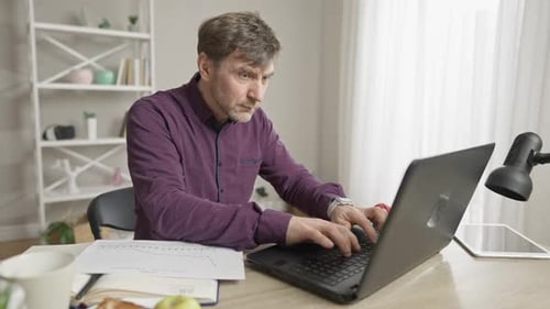 Porträt eines vielbeschäftigten kaukasischen männlichen Mitarbeiters, der online Nachrichten sendet und Kaffee trinkt