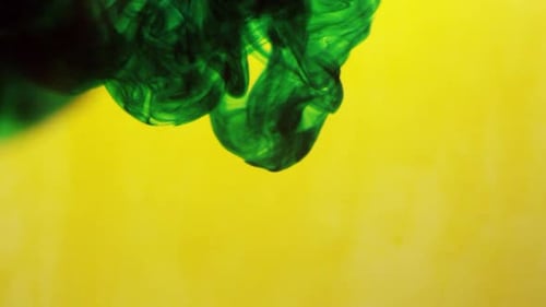 Green and yellow ink mixing together in water