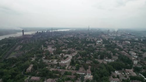 Luftaufnahme der Stadt in der Nähe einer großen Industrieanlage mit Rohren und Rauch