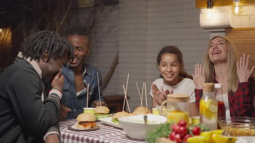 Friends Laughing and Eating Burgers at Night