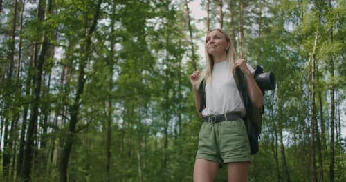 Slow Motion: Adult Caucasian Woman Wearing Shorts and T-shirt Hikes Through Woods. Female Hiker with