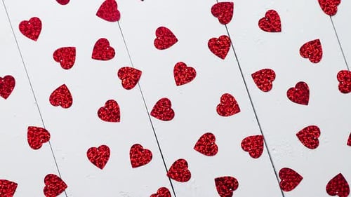 Vlentine's Day Composition. Heart Shaped Sequins Placed on White Wooden Table