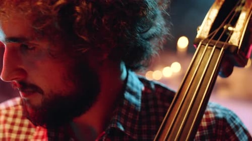 Young Adult Plays Double Bass in Moody Lighting