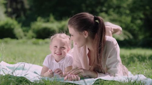Mom And Child Lying And Resting On Blanket At Park