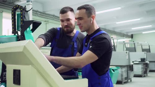 Two Factory Workers are Discussing Near the Machine