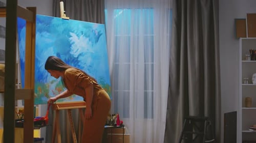 Young Woman Painting Abstract Artwork in Studio