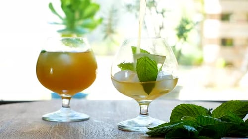 Verser le kombucha dans un verre avec de la glace et des feuilles de menthe ; rétroéclairage lumineux
