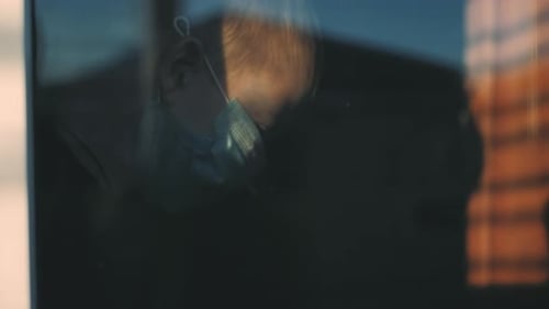 Child wearing face mask seen through window