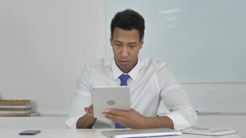 Young Adult Looks At Tablet in Office