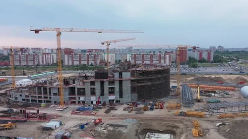 Grúas altas cerca del edificio del estadio con marcos de metal en la ciudad