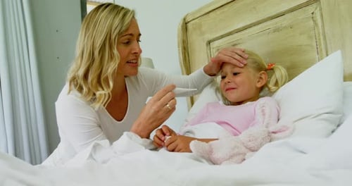 Woman Checks Little Girl's Temperature at Home