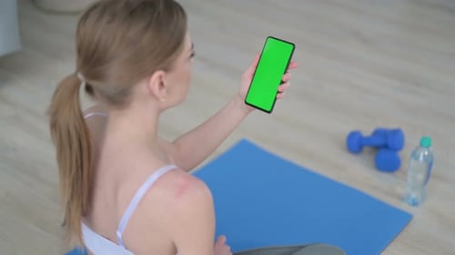 Rear View of Young Woman Using Smartphone with Chroma Key Screen on Yoga Mat