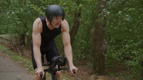 Superzeitlupen-Triathlet fährt Fahrrad Profi-Radfahrer fährt auf einer Waldstraße Vorbereitung für