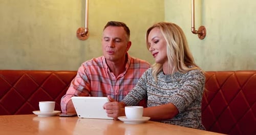 Couple Uses Tablet in Restaurant Booth Together