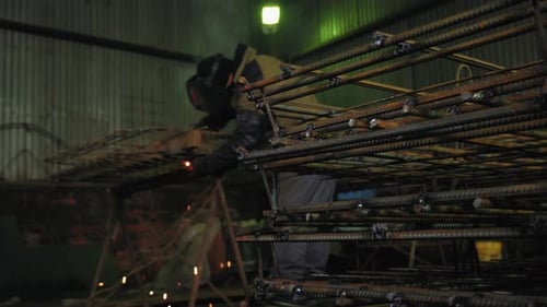Industrial Welder Working in Dark Factory at Night