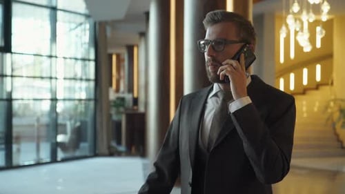 Young Businessman in Suit Standing in the Hotel Lobby and Talking on Mobile Phone Business Trip