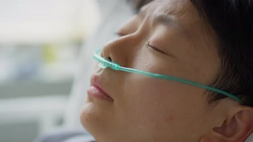 Femme asiatique avec une canule nasale se réveillant à l'hôpital