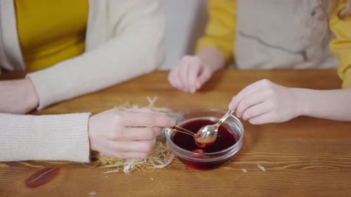 Nicht wiederzuerkennende Mutter und Mädchen färben Eier zu Ostern