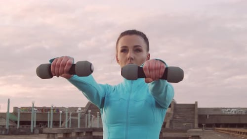 Woman Doing Dumbbell Exercises Outdoors