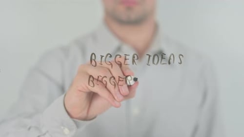 Man Writing Bigger Ideas on Whiteboard
