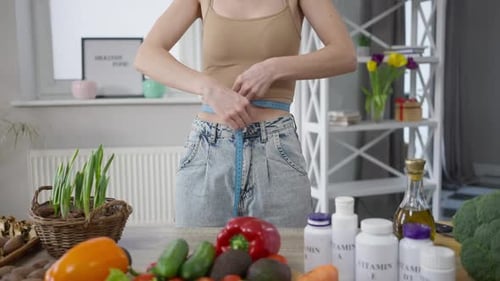 Young Woman Measures Her Waist in Bright Kitchen