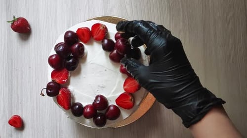 Garnishing Cake with Cherries Overhead